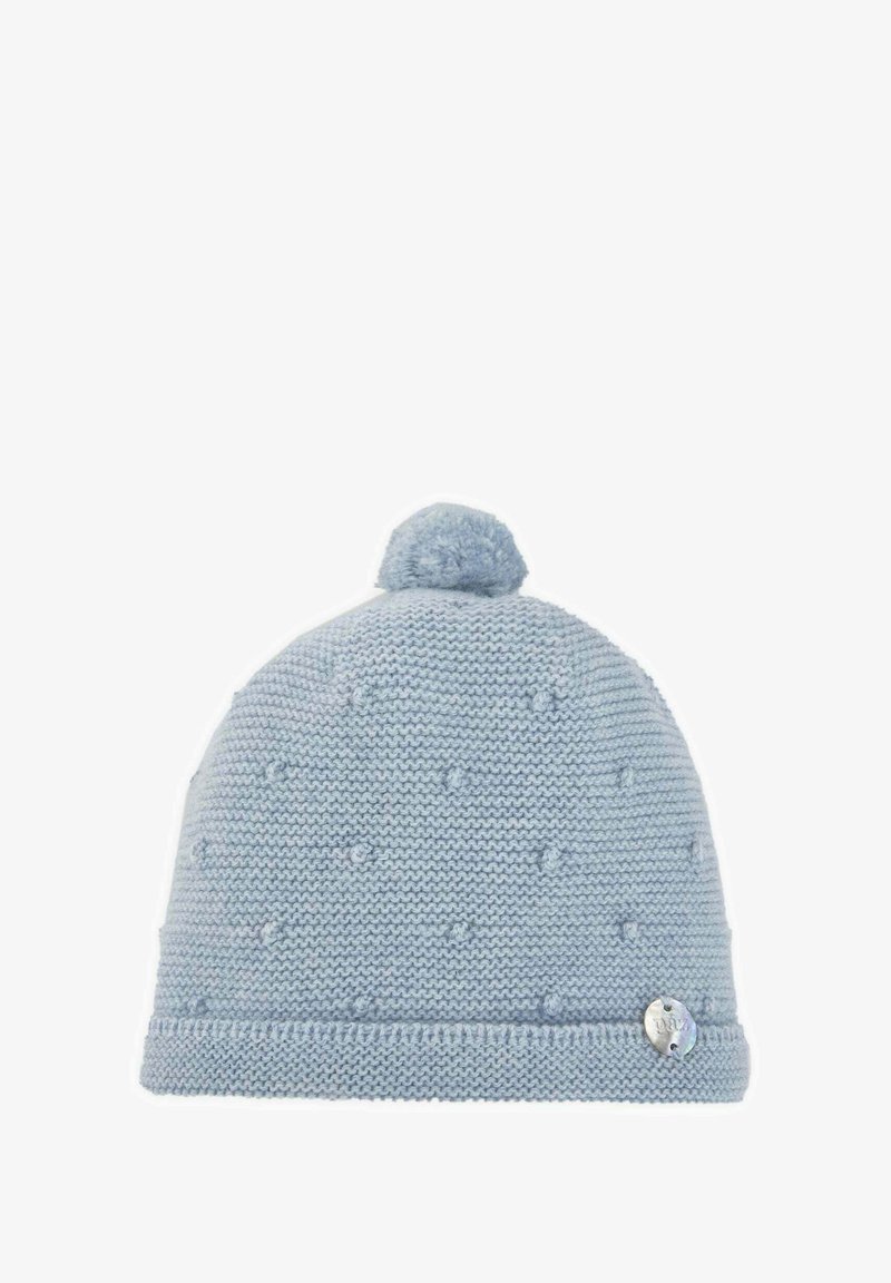 Bonnet en tricot bleu avec un pompon sur le dessus, présentant un motif texturé et une petite étiquette métallique sur le côté.