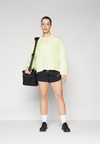 Neoonkollane kerge jope elastsete mansettidega, koos mustade lühikestega. Must kott, millel on võrkkangast detailid. Mustad kingad ja valged sokid.