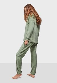 Green loungewear set with long sleeves and elastic waistband, featuring a floral print texture. Soft fabric with relaxed fit and drop shoulders.