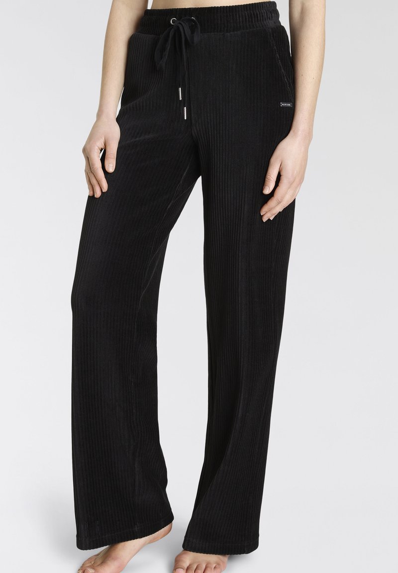 Schwarze Cordhose mit weit geschnittenen Beinen, mit einem Kordelzugbund, subtiler Textur und vertikalem Rippmuster.