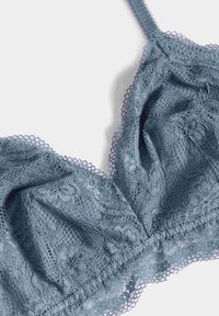 Reggiseno blu di pizzo con spalline regolabili, motivo floreale e bordi ondulati, caratterizzato da una trama morbida e una costruzione leggera.