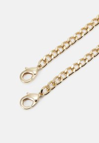 Łańcuszek z metalu w odcieniu złota z owalnymi ogniwami i dwoma zapięciami typu karabińczyk na każdym końcu, o błyszczącym wykończeniu i gładkiej fakturze.