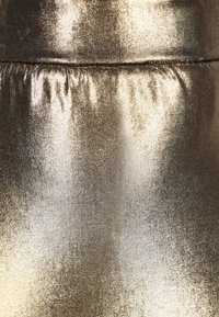 Kultainen metallifabric, jossa on sileä rakenne, hienovaraisia laskoksia ja lievä kiilto, luoden kimaltelevan visuaalisen vaikutelman.