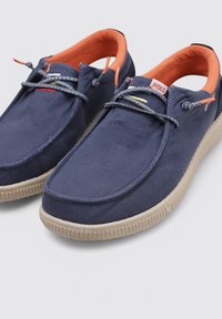 Zapatos de lona navy con suelas de goma beige, cordones grises y forro naranja. Cuentan con un diseño de perfil bajo y puntera reforzada.