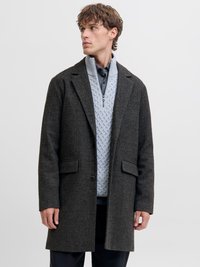 Mørk grå fiskebensmønstret frakk med en strukturert design, to lommer foran og en enkel knapplukking; lagdelt over en lys grå teksturert genser.