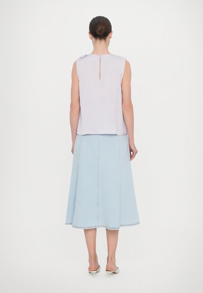 Top fără mâneci, de culoare mov deschis, cu un detaliu în formă de cheie la spate, asortat cu o fustă midi din denim albastru deschis, cu un design evazat și cusături vizibile.
