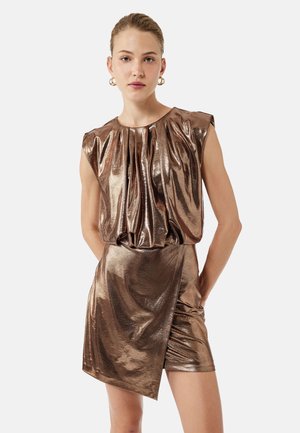 Robe en bronze métallique avec un corsage plissé et des manches courtes, mettant en avant une silhouette ajustée et un détail de jupe drapée asymétrique.