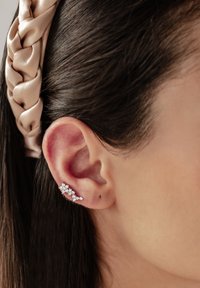 Orecchino a cuff in argento con cristalli trasparenti sparsi, caratterizzato da un design contemporaneo che mette in mostra pietre di diverse dimensioni e forme.