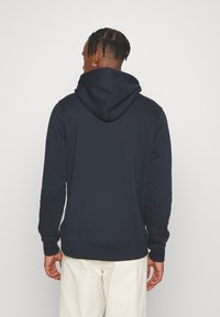 Mörkblå sweatshirt med huva, långa ärmar och ribbad nederkant. Tillverkad av ett mjukt tyg med en slät yta.