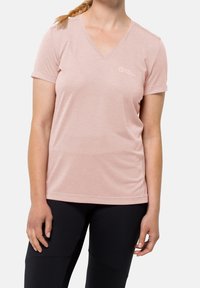 Ljusrosa, kortärmad V-ringad t-shirt i mjukt tyg, med en diskret logotyp på vänster bröst och en avslappnad passform. Svarta leggings.