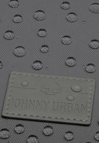 Szürke, textúrált felületű anyag, vízcseppekkel és egy "JOHNNY URBAN" feliratos, domború gumitaggal.
