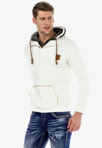 White hooded sweatshirt with textured black interior, brown drawstrings, and front pocket. Worn with blue distressed jeans.