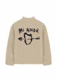 Pullover in pile beige con collo alto, caratterizzato da una stampa grafica nera con cuore e freccia e testo "Mi Amor". Texture morbida.
