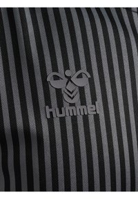 Sort og grå stribet stof med en struktureret overflade og et Hummel-logo i grå, der har et bi-design over mærkenavnet.