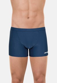 Shorts de bain bleu marine en tissu extensible, avec une coupe ajustée, une texture lisse, et un motif hexagonal à l'avant. Logo affiché sur le côté.