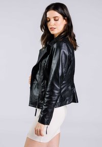 Svart lädermotorcykeljacka med dragkedja framtill, utsvängd krage och texturerad finish. Har sidofickor och dragkedjor på ärmarna.