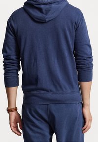 Mörkblå hoodie med dragsko, ribbade ärmar och midja, tillverkad av mjukt bomullsblandat tyg som visar en slät textur och minimalistisk design.