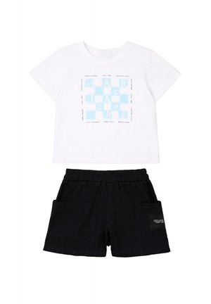 T-shirt bianca a maniche corte con logo quadrato blu e pantaloncini neri con elastico in vita, tasche laterali e una piccola toppa.