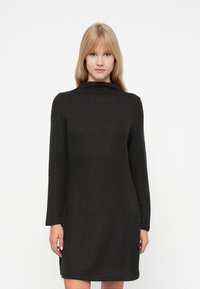 Μαύρο, φόρεμα σε στυλ πουλόβερ με ψηλή λαιμόκοψη, μακριά μανίκια και ριγωτή υφή. Φτάνει πάνω από τα γόνατα με πλαϊνές σχισμές.