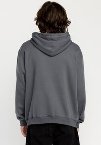 Grå hættetrøje lavet af blødt stof, med en stor hætte, ribbede manchetter og en båndet kant. Glat tekstur med et afslappet fit design.