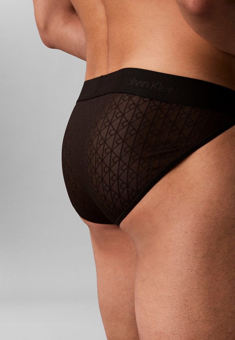 Schwarze Calvin Klein Slips mit einem strukturierten Mesh-Design und einem Rautenmuster, elastischem Bund und nahtlosen Kanten für einen smoothen Sitz.