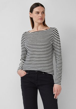 Long-sleeve striped top in black and white, with a boat neckline and fitted silhouette. Worn with black pants. Smooth fabric texture.