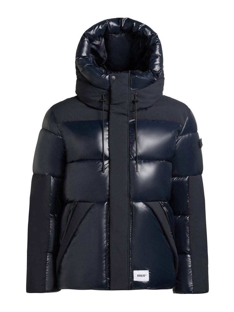 Mornarsko modra puhovka z visokim ovratnikom, sijočo površino, elastiko za zategovanje in stranskimi žepi. Ima logotip na sprednjem robu.