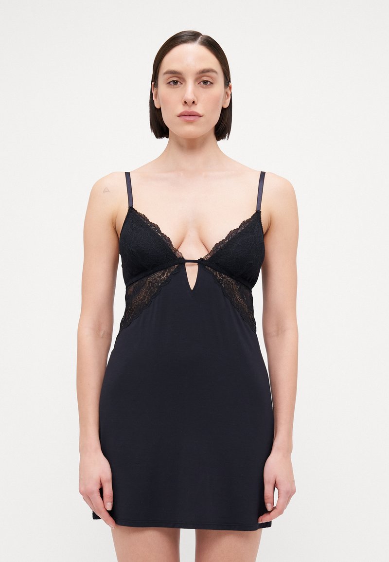 Fekete pántos top csipkés díszítéssel a melleknél, állítható pántokkal és kulcslyuk kivágással a középső elülső részen. Simább anyagfel�ület.