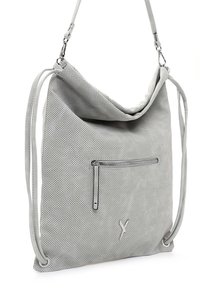 Sac à épaule gris clair perforé avec des bretelles réglables et une poche zippée à l'avant, suspendu par des fermoirs métalliques.