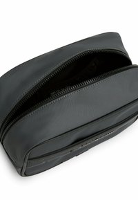 Palla da toeletta nera con zip, dal texture liscia e opaca. Presenta scomparti interni e cuciture a contrasto lungo la zip.