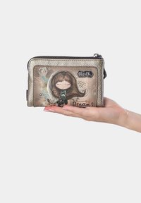 Cartera con cremallera en acabado plateado metálico, que presenta una ilustración de una chica y el texto "Sueños", con patrones decorativos y un pequeño acento verde.