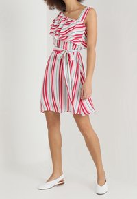 Monivärinen raitamekko, jossa on nyörillinen olkaimeton muotoilu, värikkäitä raitoja punaisena, vaaleanpunaisena ja vaaleanssinä, ja siihen kuuluu yhteensopiva vyö.