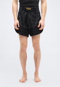 Μαύρα αθλητικά σορτς με υφή, κίτρινο λογότυπο Venum και εφαρμοστό ελαστικό στην μέση. Κοντό μήκος με πλαϊνές σχισμές για μεγαλύτερη κινητικότητα.