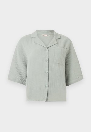 Camisa de manga corta verde claro con tela texturizada, bolsillo delantero en el pecho y cuello relajado.