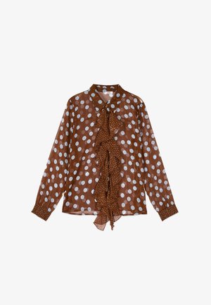 Braune, langärmelige Bluse mit weißen Polka-Dots, vorne mit Knöpfen und einem gerafften Stoffstreifen, der vertikal in der Mitte verläuft.