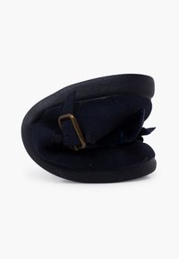 Zapatilla de ante azul marino con suela redondeada, que presenta una correa con hebilla de metal y una textura suave, diseñada para la comodidad y un fácil uso.