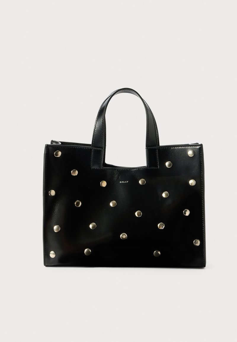 Black leather tote bag featuring metallic studs, structured shape, dual handles, and a zipper closure. Simple logo design on the front.