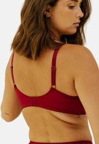 Soutien-gorge bourgogne avec bretelles réglables, bande texturée et fermeture à crochet. Présente un tissu doux et un design minimaliste.