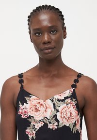 Μαύρο φλοράλ φόρεμα με λαιμόκοψη σε V, διακοσμημένο με ροζ τριαντάφυλλα και πράσινα φύλλα. Ρυθμιζόμενοι ιμάντες στολισμένοι με μαύρες φλοράλ λεπτομέρειες.