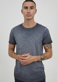 Marineblå, kortermet t-skjorte med en subtil gradienttekstur, rund halslinning og rullede ermekanter. Minimalistisk design med et merke nederst.