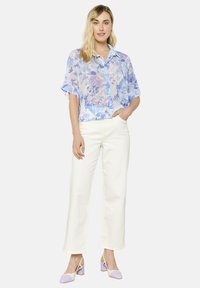 Lengvas, permatomas mygtukų marškinėliai su mėlynu gėlių raštu, derinami su baltais plačiais kelnėmis ir levandų akcentais papuoštomis aukštakulniais.