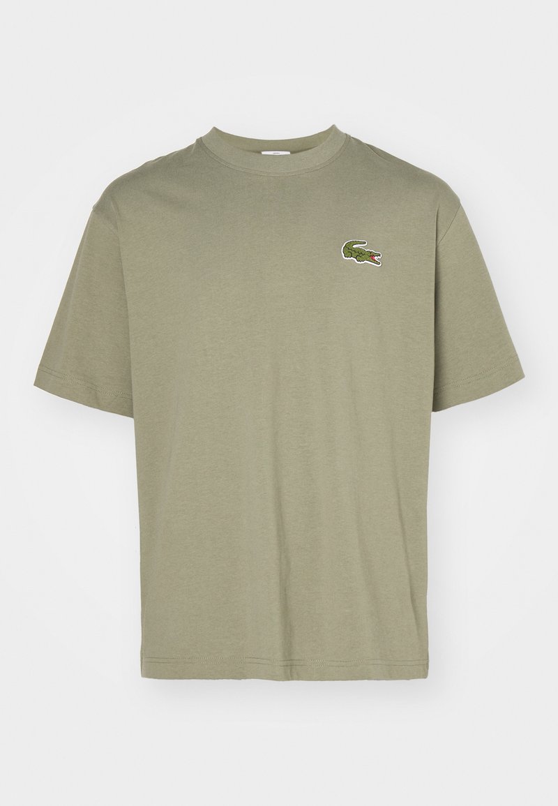 T-shirt en coton vert olive avec un col rond, des manches courtes et un logo de crocodile brodé sur la poitrine gauche.