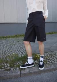Svarta knälånga shorts med rak skärning och synliga sidfickor. Matchas med vita ankelstrumpor och svarta sneakers. Texturerad stickad topp med stjärndesign.
