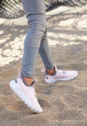 Pink sporty sneakers with gray accents, designed with a slip-on style and cushioned sole, paired with gray form-fitting leggings.