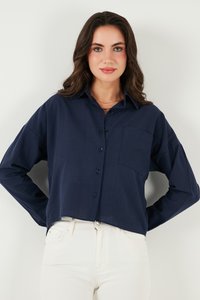 Navy blue button-up shirt with a collar, long sleeves, and a chest pocket. Made of lightweight fabric, it has a cropped design and smooth texture.