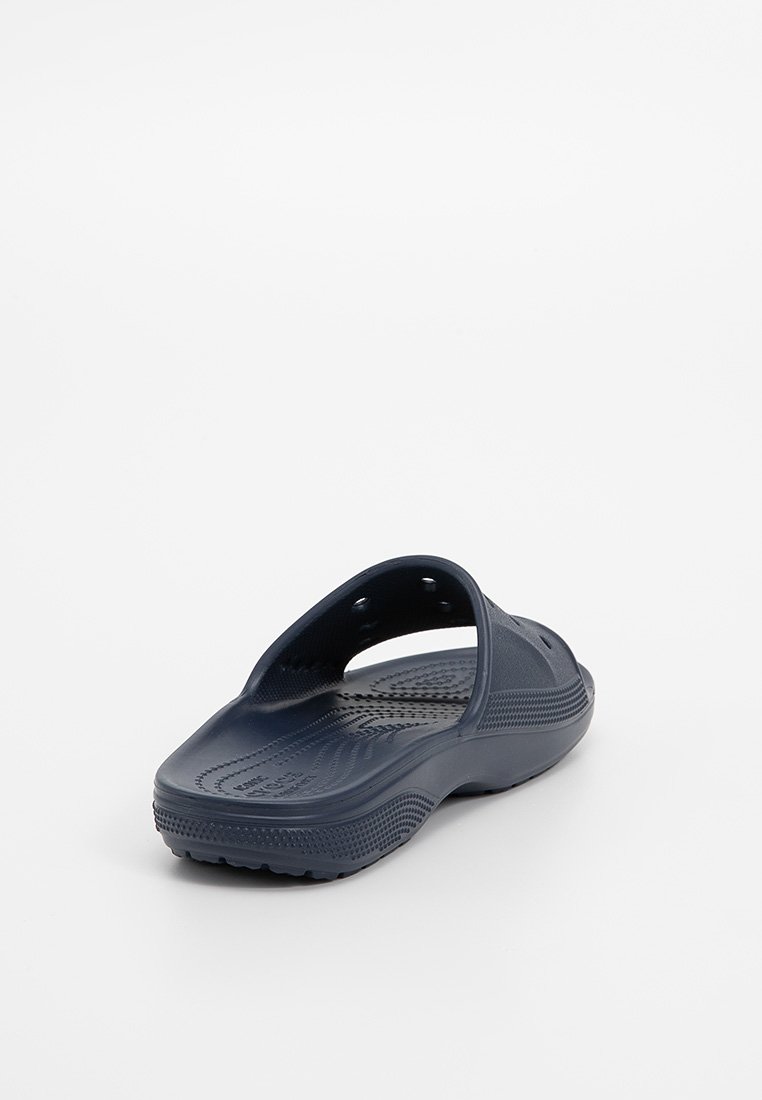 Marineblauwe instaprubberen sandaal met een gestructureerde voetbed, ventilatiegaten en een patroon op de zool, gefotografeerd op een witte achtergrond.