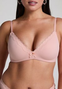 Ljusrosa ribbad bh med spetskant längs halslinningen, med en mittsladd detalj och justerbara axelband.