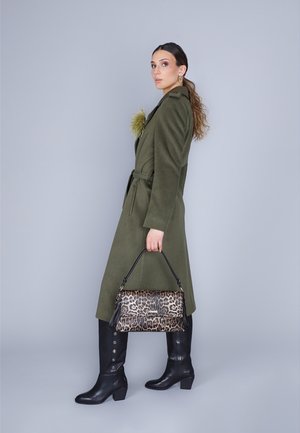 Cappotto verde oliva con vita cintata, abbinato a una borsa con stampa leopardata e stivali neri fino al ginocchio con dettagli a bottoni.