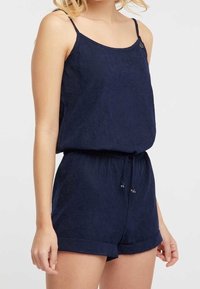 Combinaison bleu marine avec bretelles spaghetti réglables, un haut décontracté, une taille élastique et des shorts à ourlet retourné. Tissu texturé avec un léger éclat.