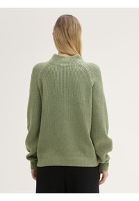 Groene geribde trui met een hoge kraag, ontspannen pasvorm en lange mouwen. Zachte gebreide textuur met een subtiel verticaal patroon.